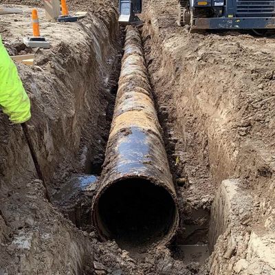 A large pipe is being installed in a trench.