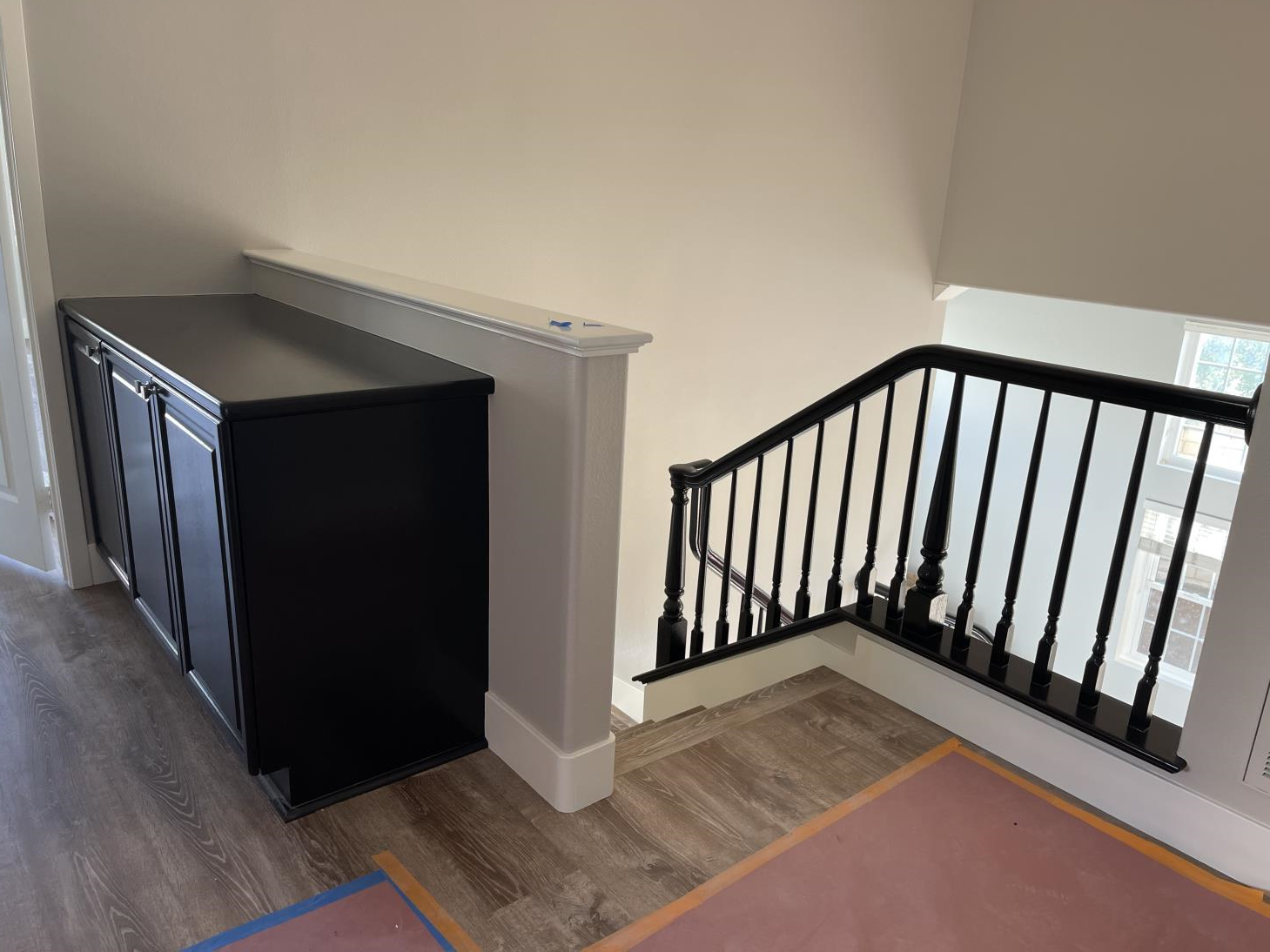 A staircase with a black railing and a black cabinet next to it.