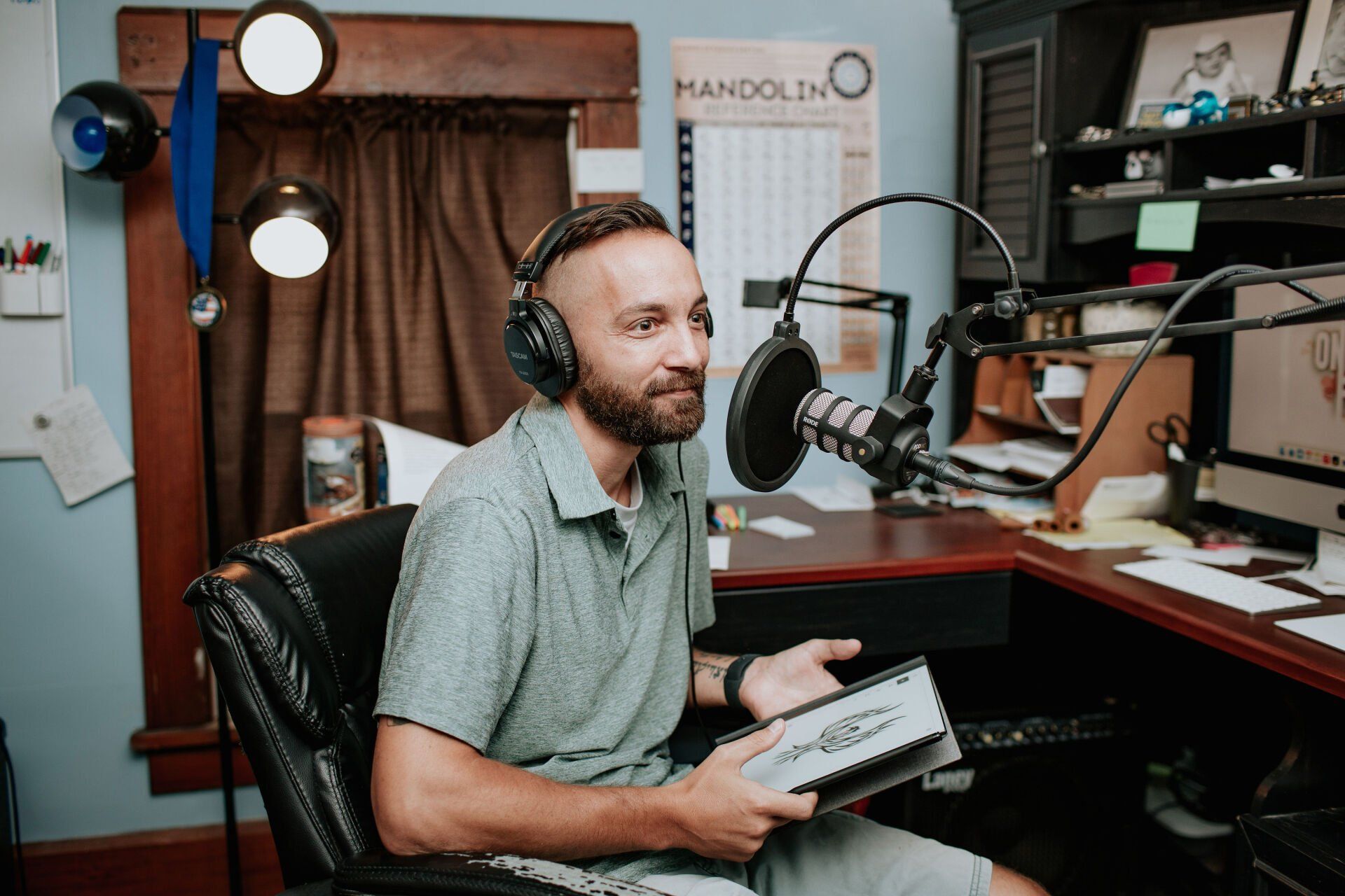 A man wearing headphones is sitting in front of a microphone.