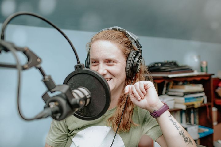 A woman wearing headphones is talking into a microphone.
