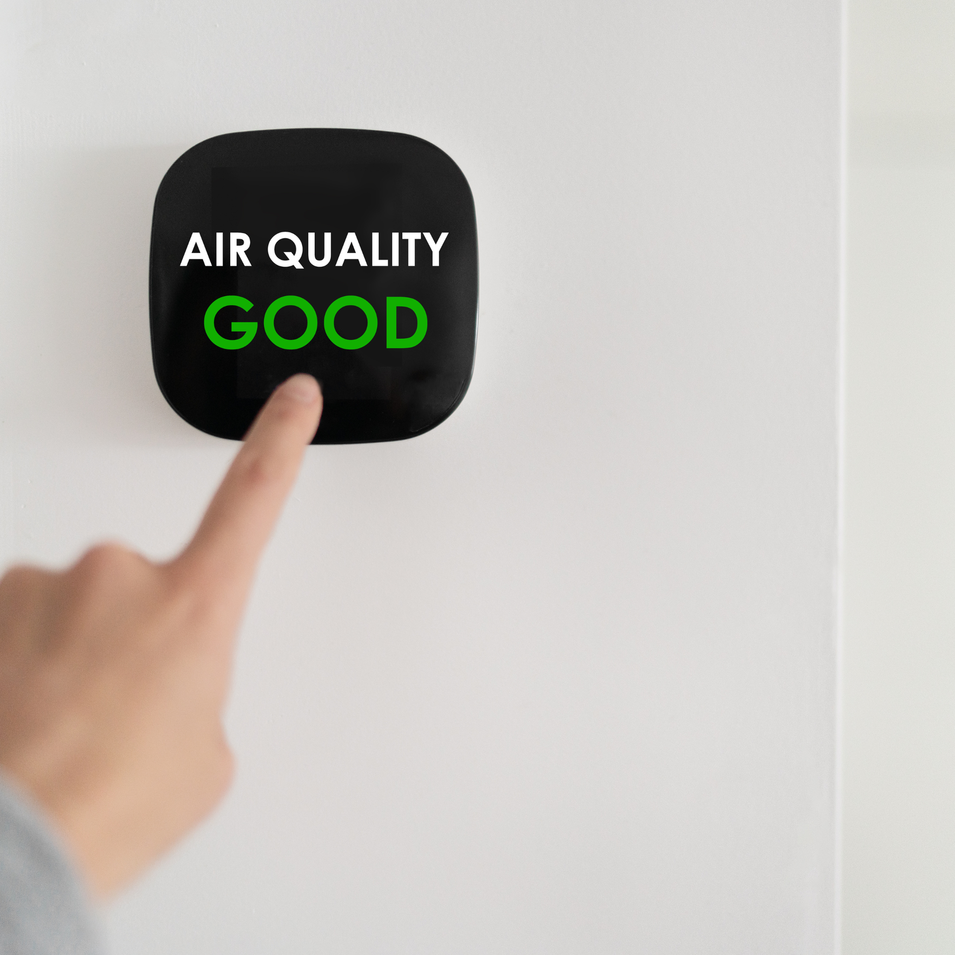 Hand pointing at a black air quality monitor showing 