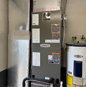 HVAC unit and water heater in a utility room. Gray Lennox unit, silver ductwork, white water heater.