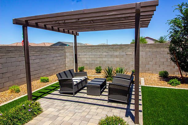 Freestanding dark wood pergola over garden furniture.
