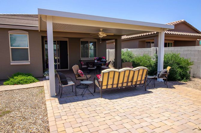 Solid tan patio cover over a brick paver seating area.