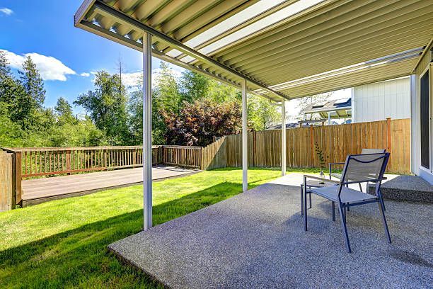 Minimalist white metal pergola on a backyard concrete patio.