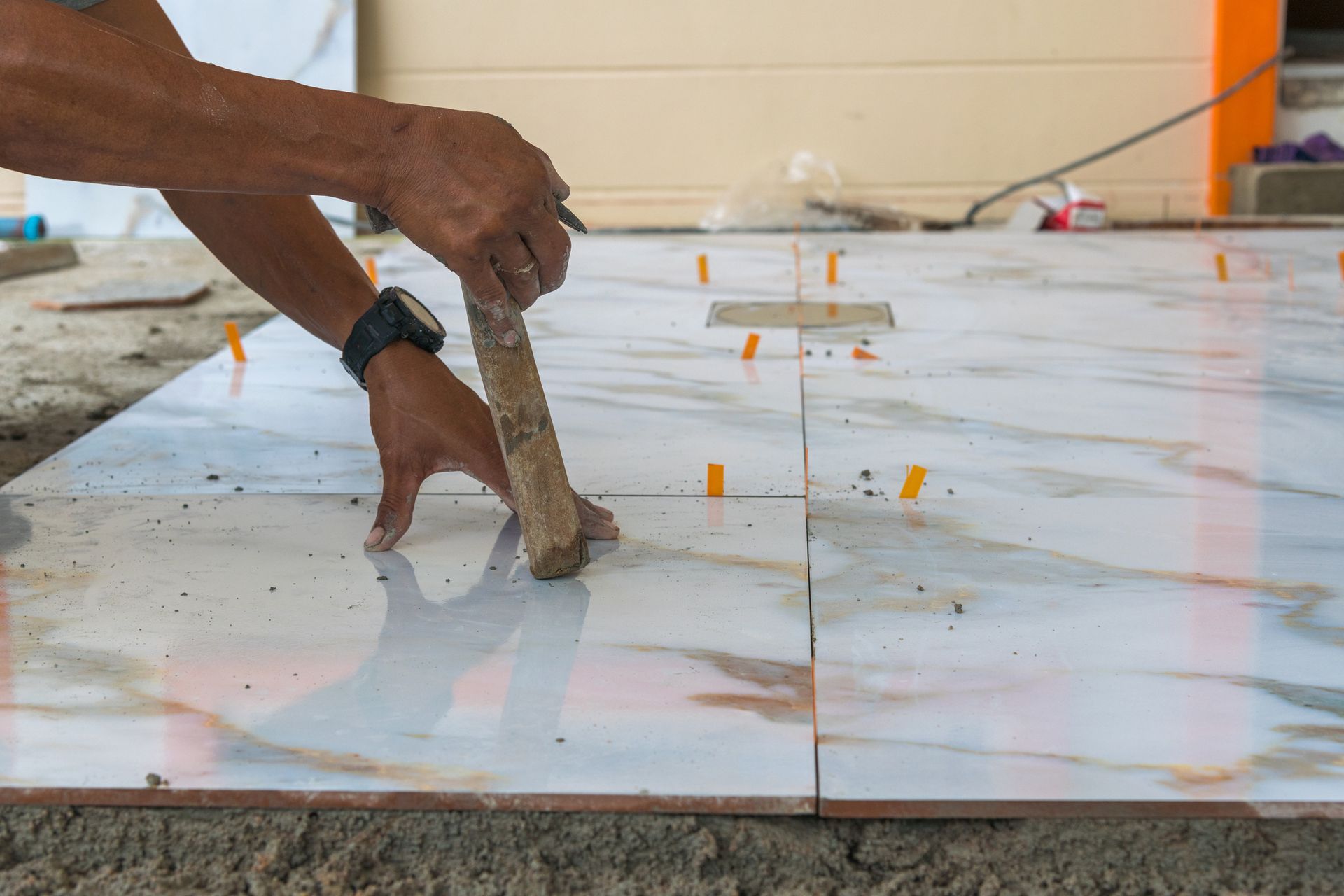 Person Laying White and Marble-Veined Tiles — San Antonio, TX — Villa Tile Service