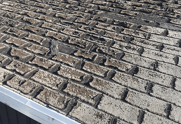 A close up of a brick roof with a gutter.