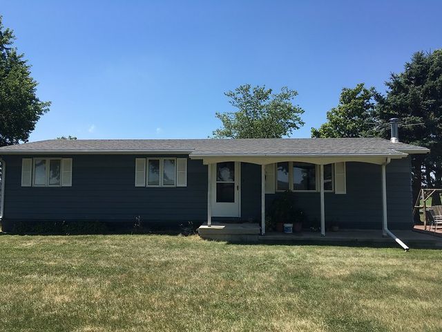 A blue house with a white porch and a blue sky in the background.