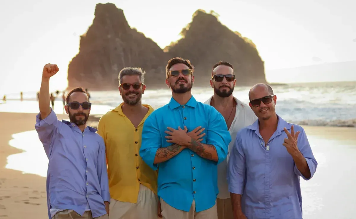 Um grupo de homens está posando para uma foto na praia.