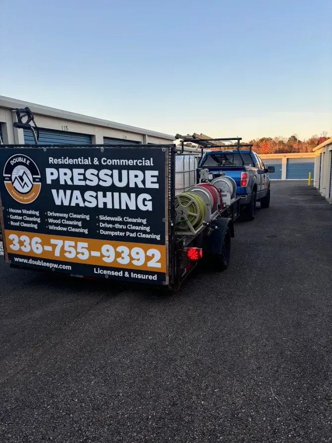 Pressure washing trailer with business logo and contact info parked in front of storage units.