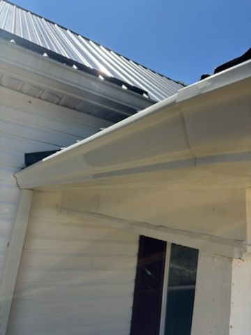 White house with a metal roof and gutters. Sunny daytime shot.