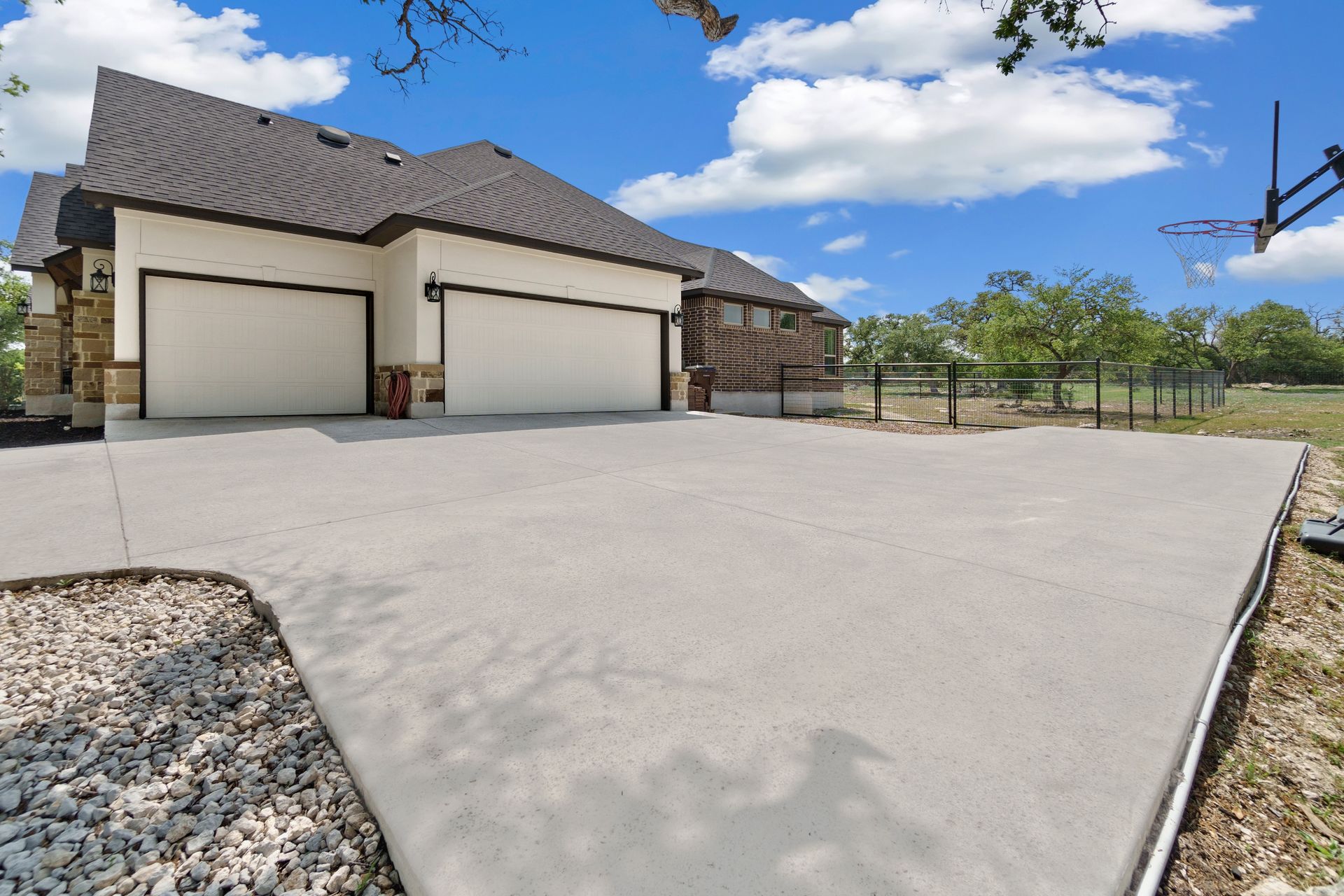 Exterior view of a house with a concrete driveway, two garage doors, and a basketball hoop.