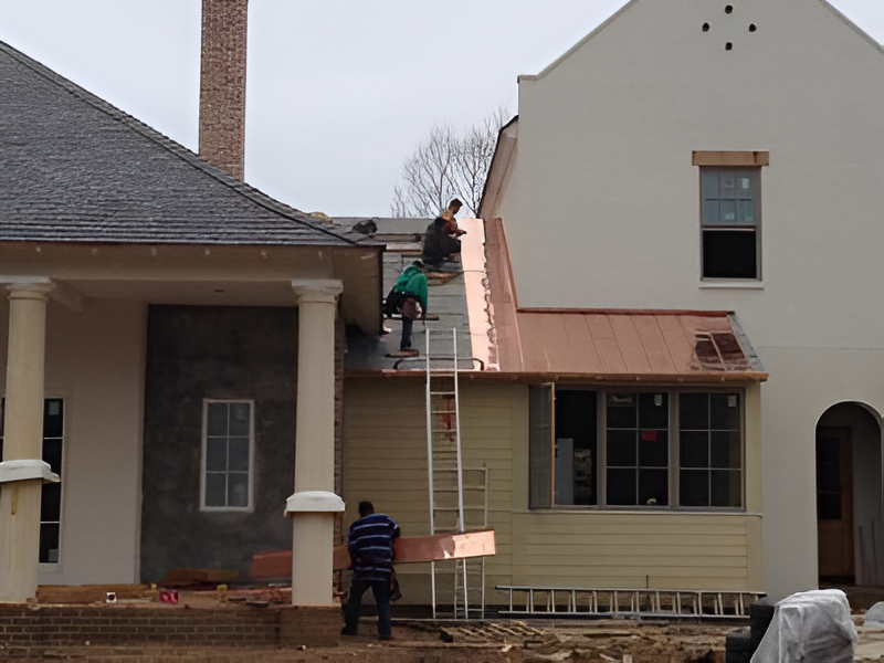 Construction workers on rooftops installing copper roofing. Building exterior with ladders and materials.