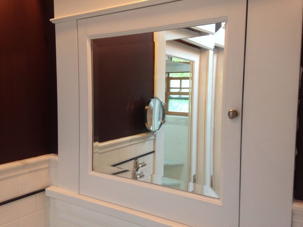 White bathroom cabinet with mirror, showing a second room and a magnified mirror.
