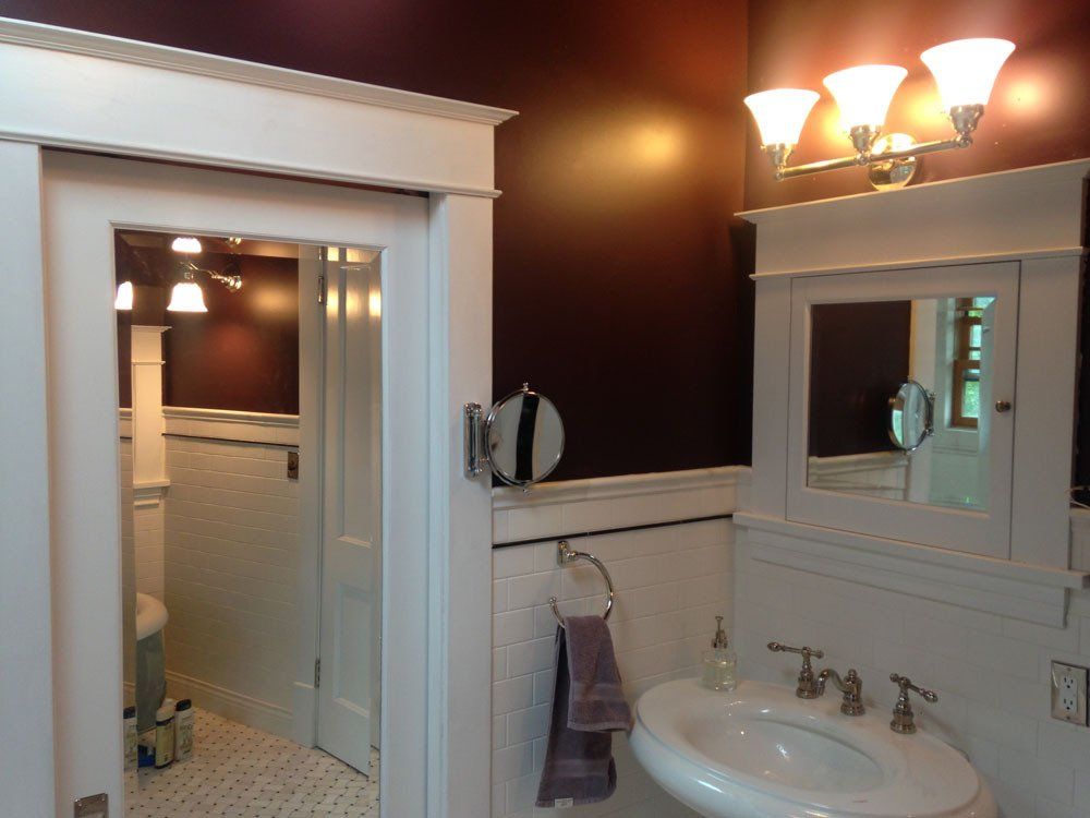 Bathroom with white wainscoting, dark purple walls, and a white sink.