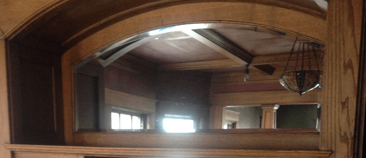Arched wooden doorway framing a room with light fixtures and a window.