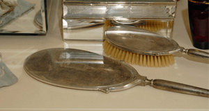 Silver vanity set with a hand mirror, brush, and other accessories.