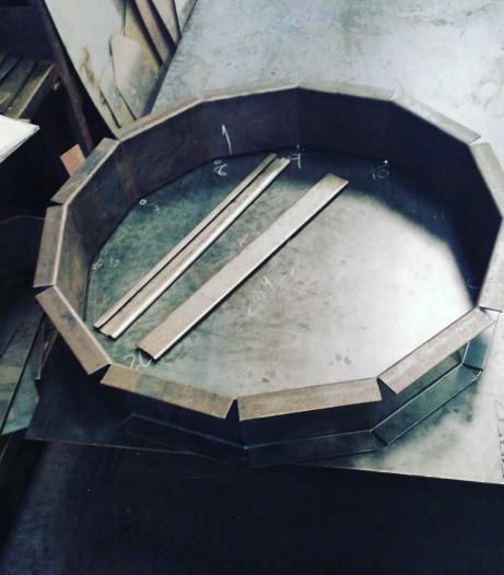 Un recipiente metálico redondo con un borde de madera se encuentra sobre una mesa.