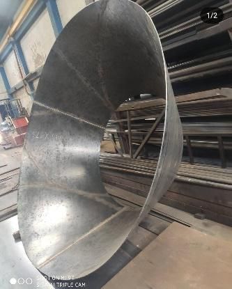 Un gran tubo de metal está colocado encima de una mesa de madera en una fábrica.