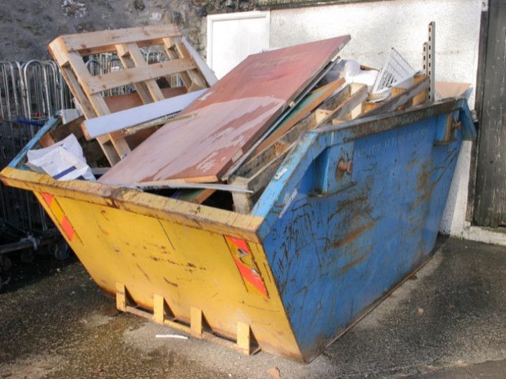 a blue and yellow dumpster filled with wooden pallets