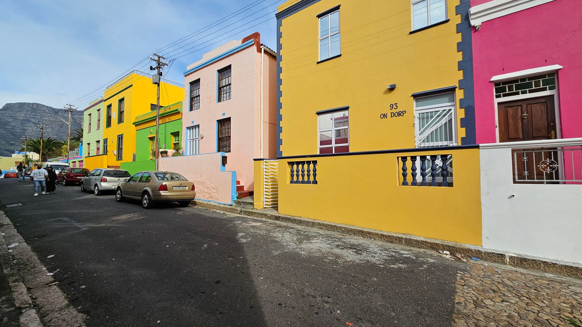 שורה של מבנים צבעוניים עם מכוניות חונות בצד הדרך.