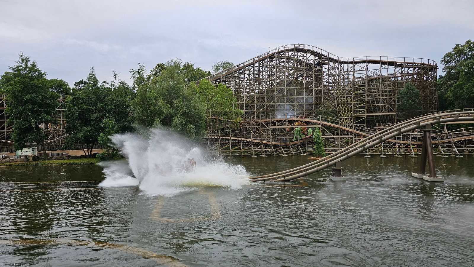 רכבת הרים מעץ מעל מים, מתיזה כשמכוניות חולפות על פניה.