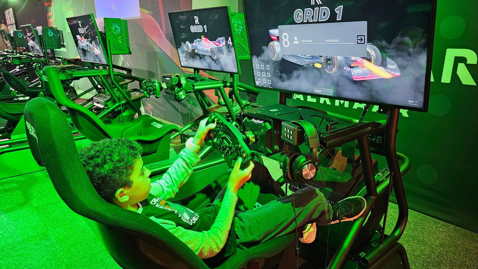 ילד בסימולטור מרוצים, ממוקד במסך, מוקף באור ירוק.