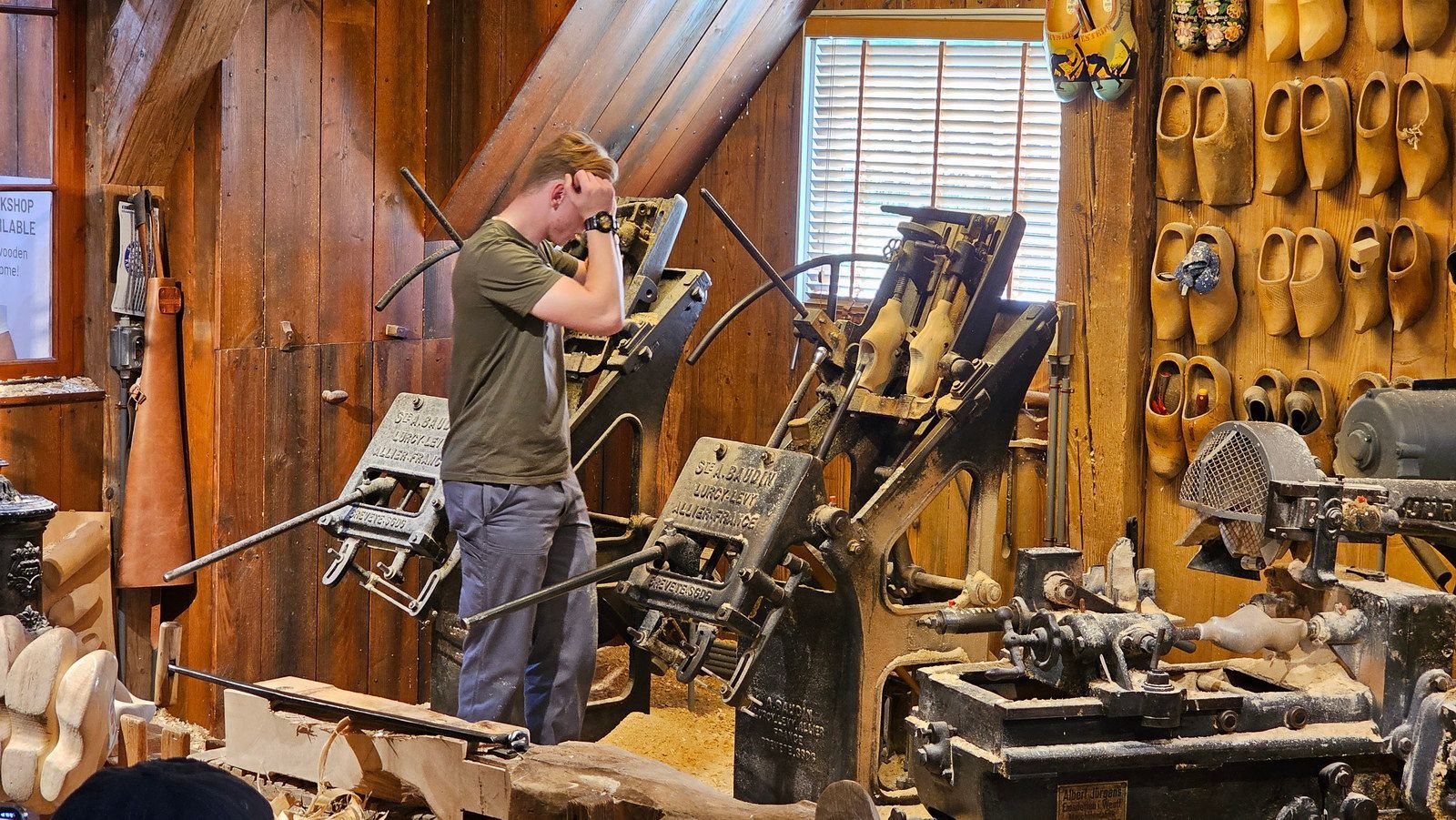 איש מגלף נעלי עץ בסדנה, באמצעות מכונות וגרגירי עץ.
