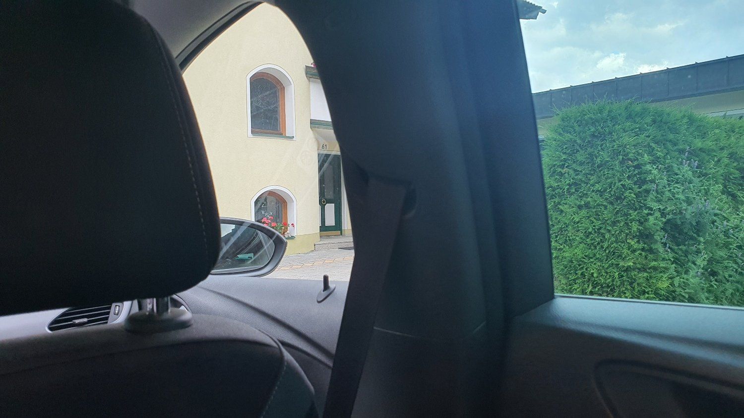 אדם יושב במכונית ומסתכל מבעד לחלון על בית.