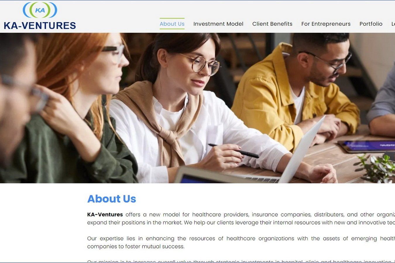 קבוצה של אנשים יושבת ליד שולחן עם מחשבים ניידים.