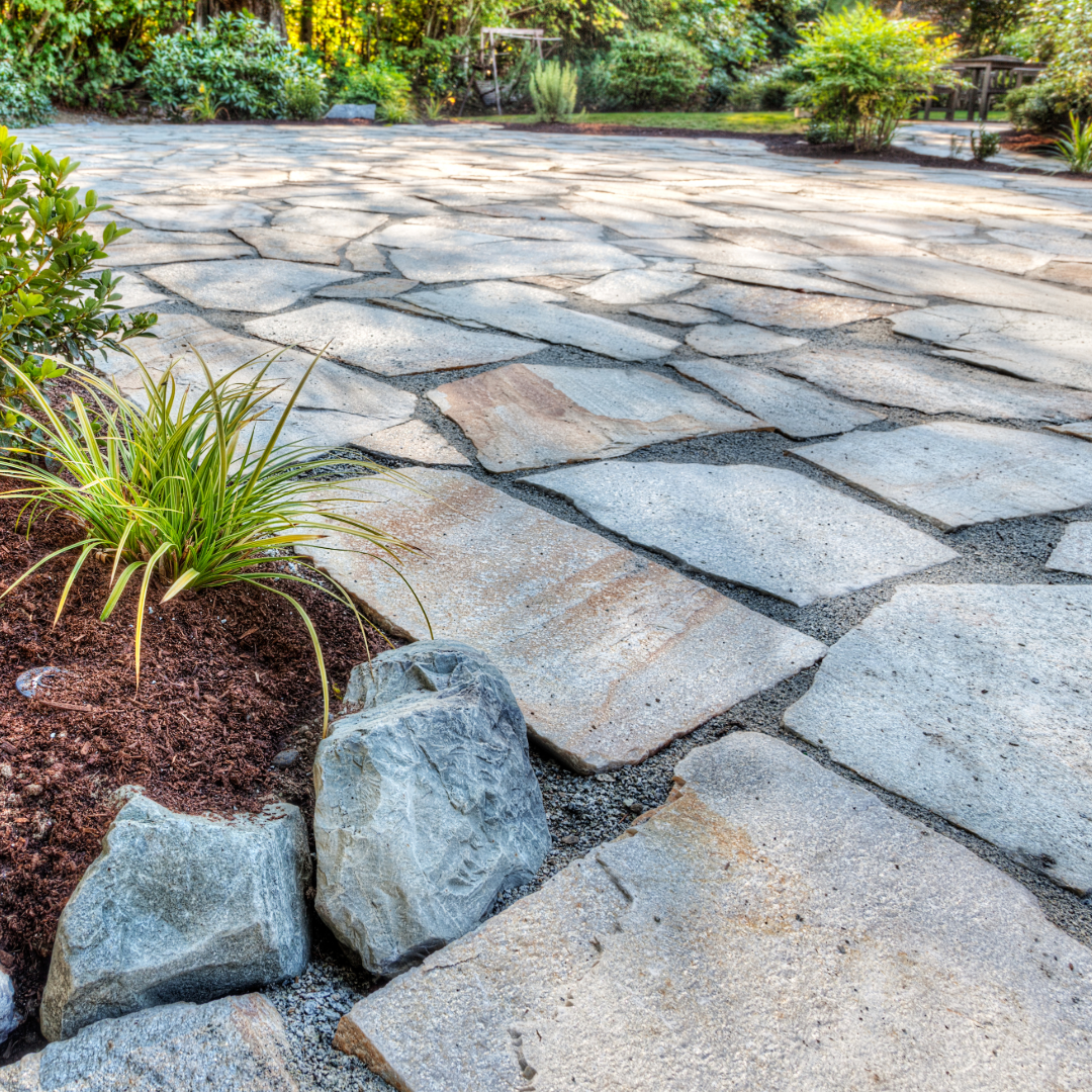 A stone patio with plants and rocks in the middle of it.