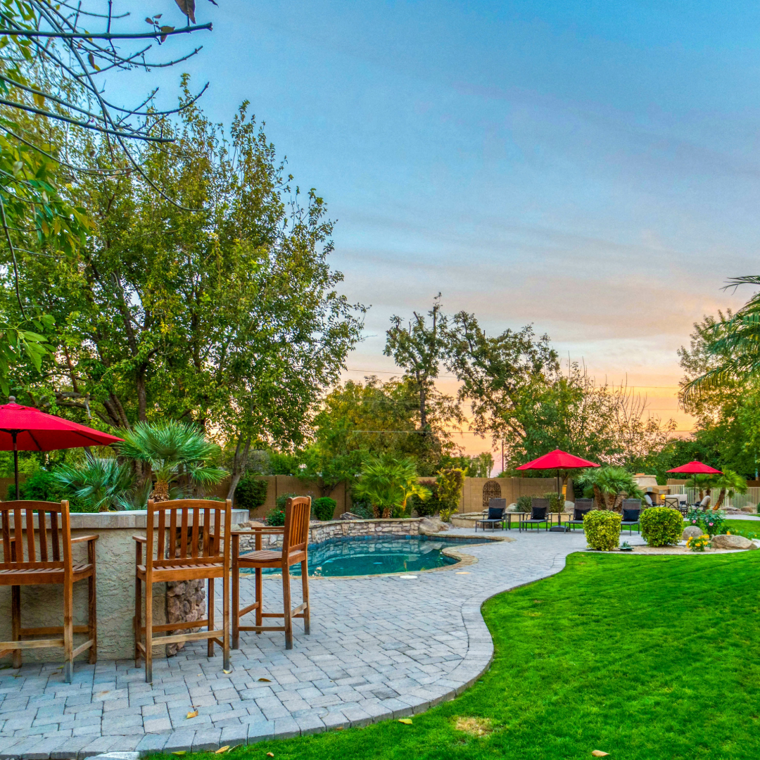 A patio with chairs and umbrellas and a pool in the background