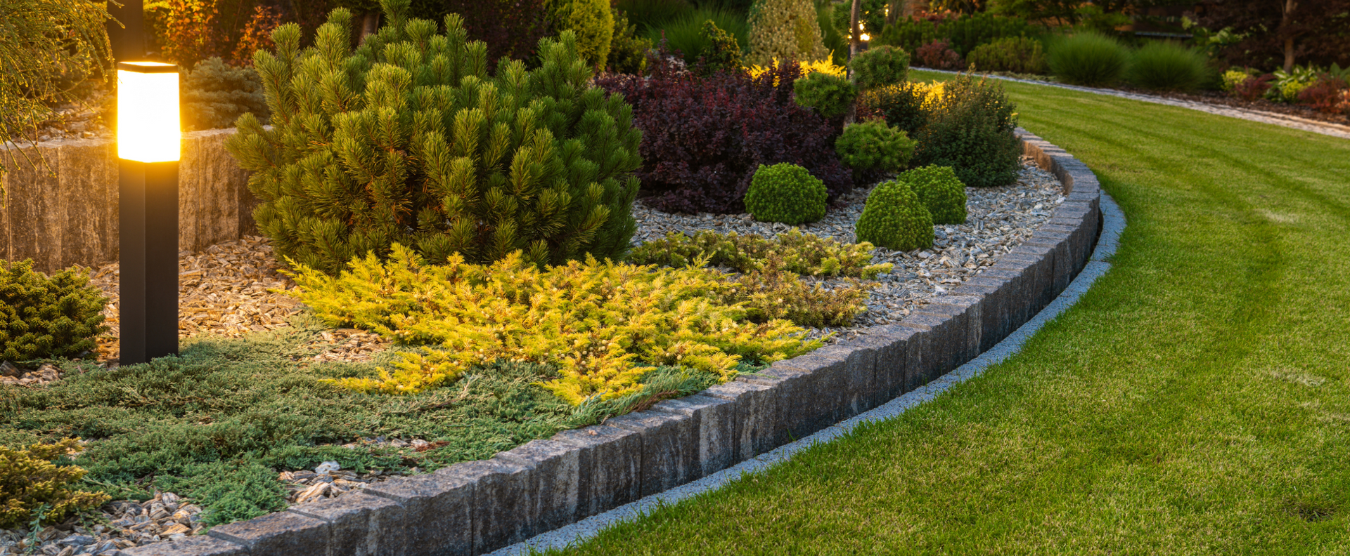 A lush green garden with a lamp post in the middle of it.