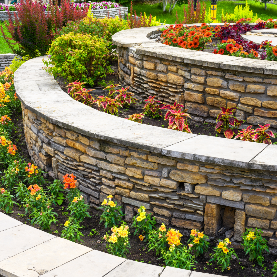 A stone wall surrounded by flowers and plants in a garden.