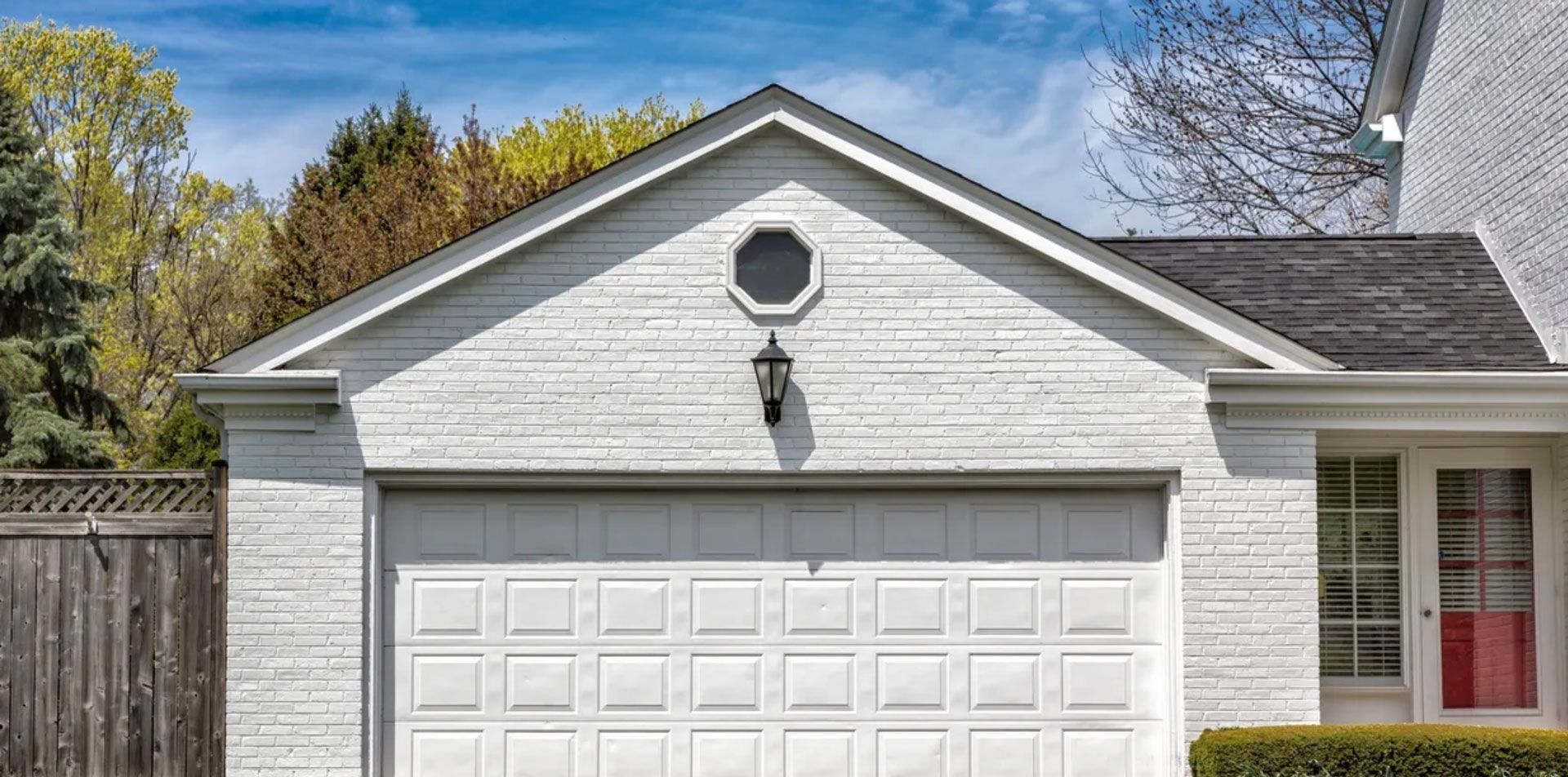 A white house with a white garage door and a red door.