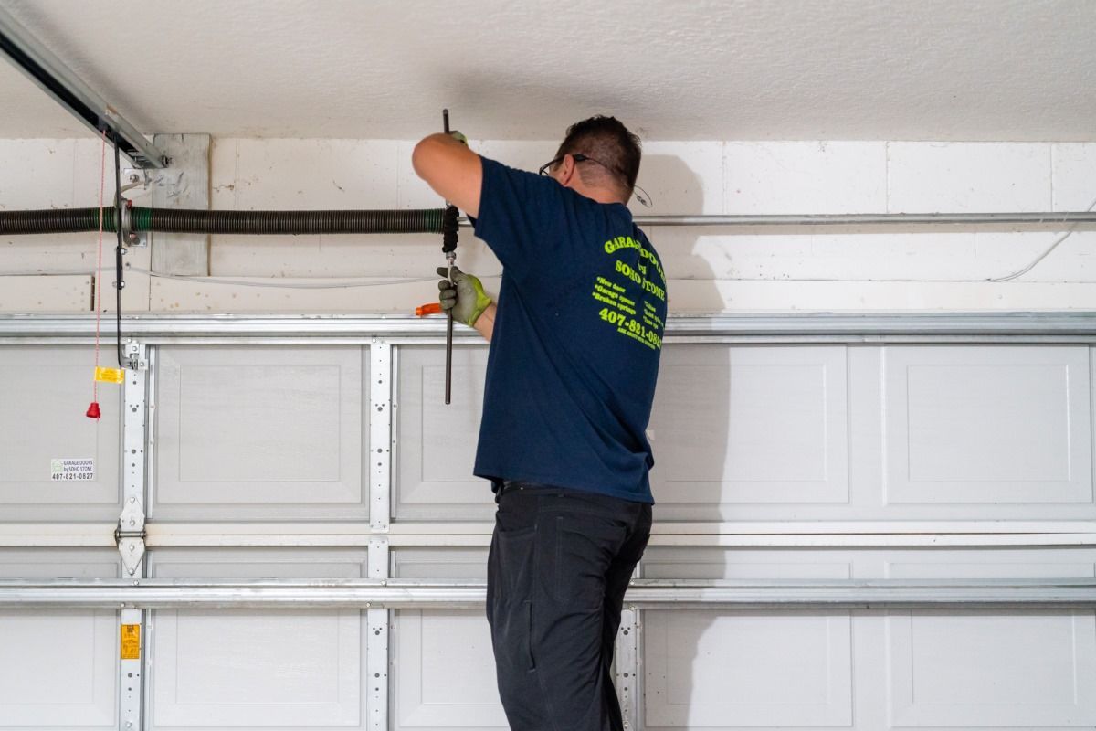 A man in a blue shirt is working on a garage door.