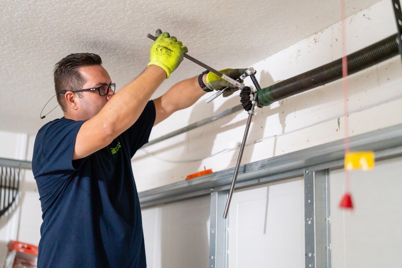 A man is fixing a garage door spring in a garage.
