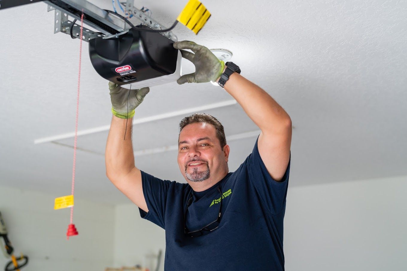 A man is fixing a garage door opener in a garage.