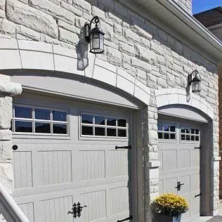 There are two garage doors on the side of a brick building.