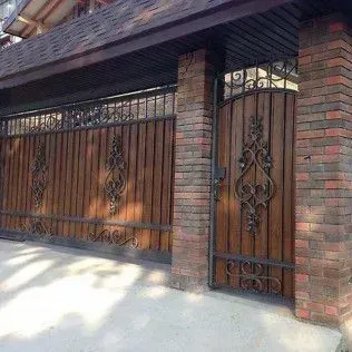 A brick building with a wooden gate and a wrought iron gate.