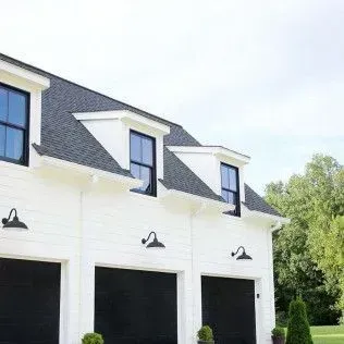 A white house with black garage doors and black windows.