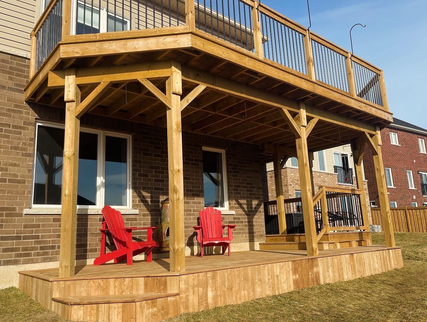 Wooden deck with stairs leading up to a multi-level deck attached to a light-colored house.