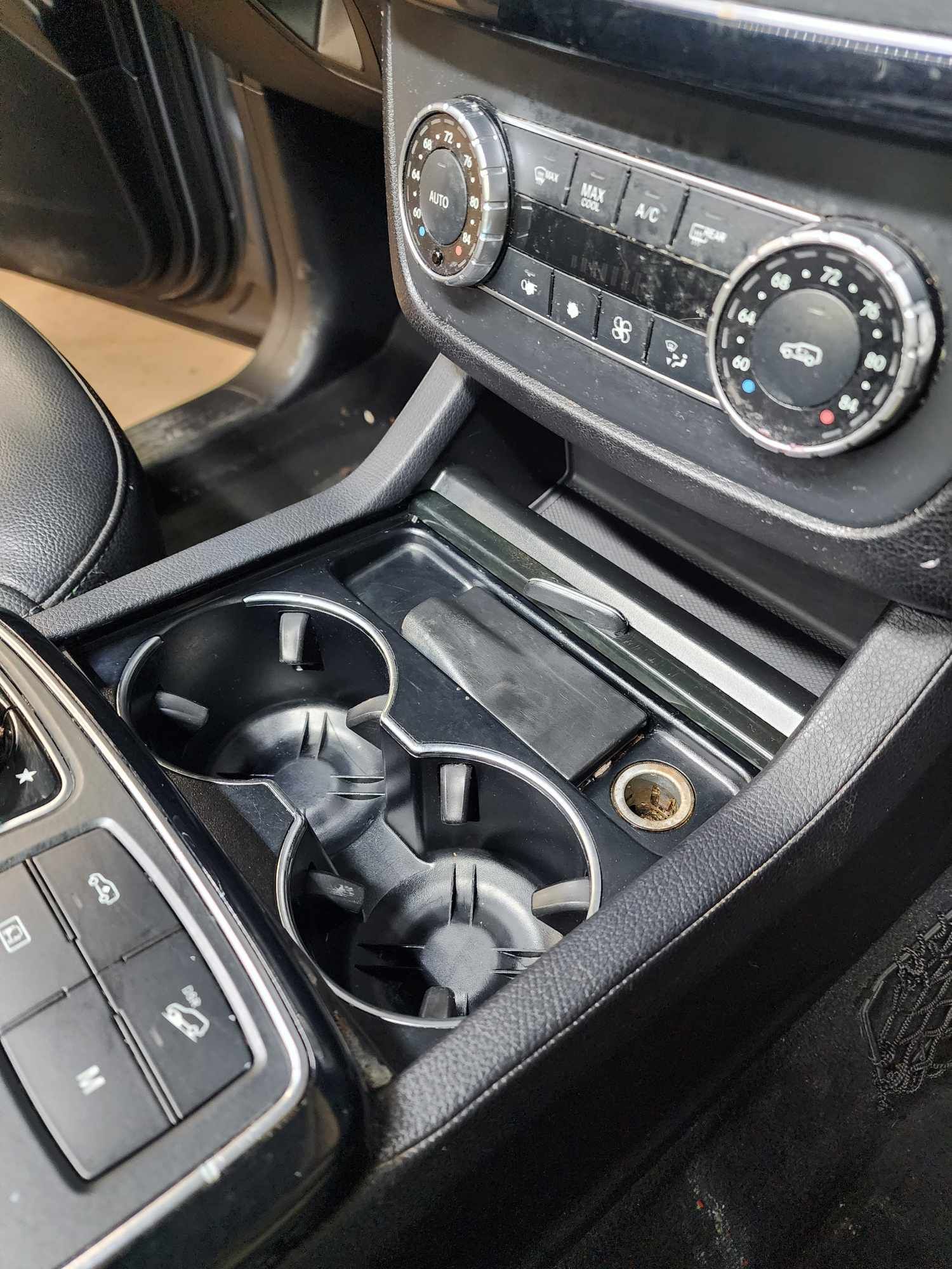 Car interior: center console with cupholders, air conditioning controls, and power outlet.