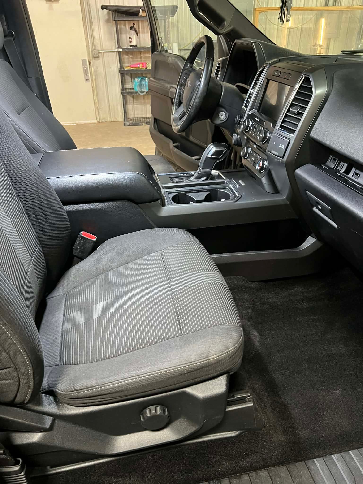 Interior of a black pickup truck. Driver's seat visible with a black seat, console, and dashboard.