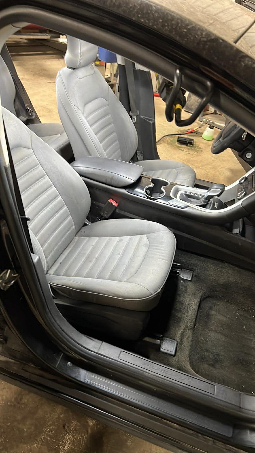Gray interior of a car, with two front seats, steering wheel, and console visible.