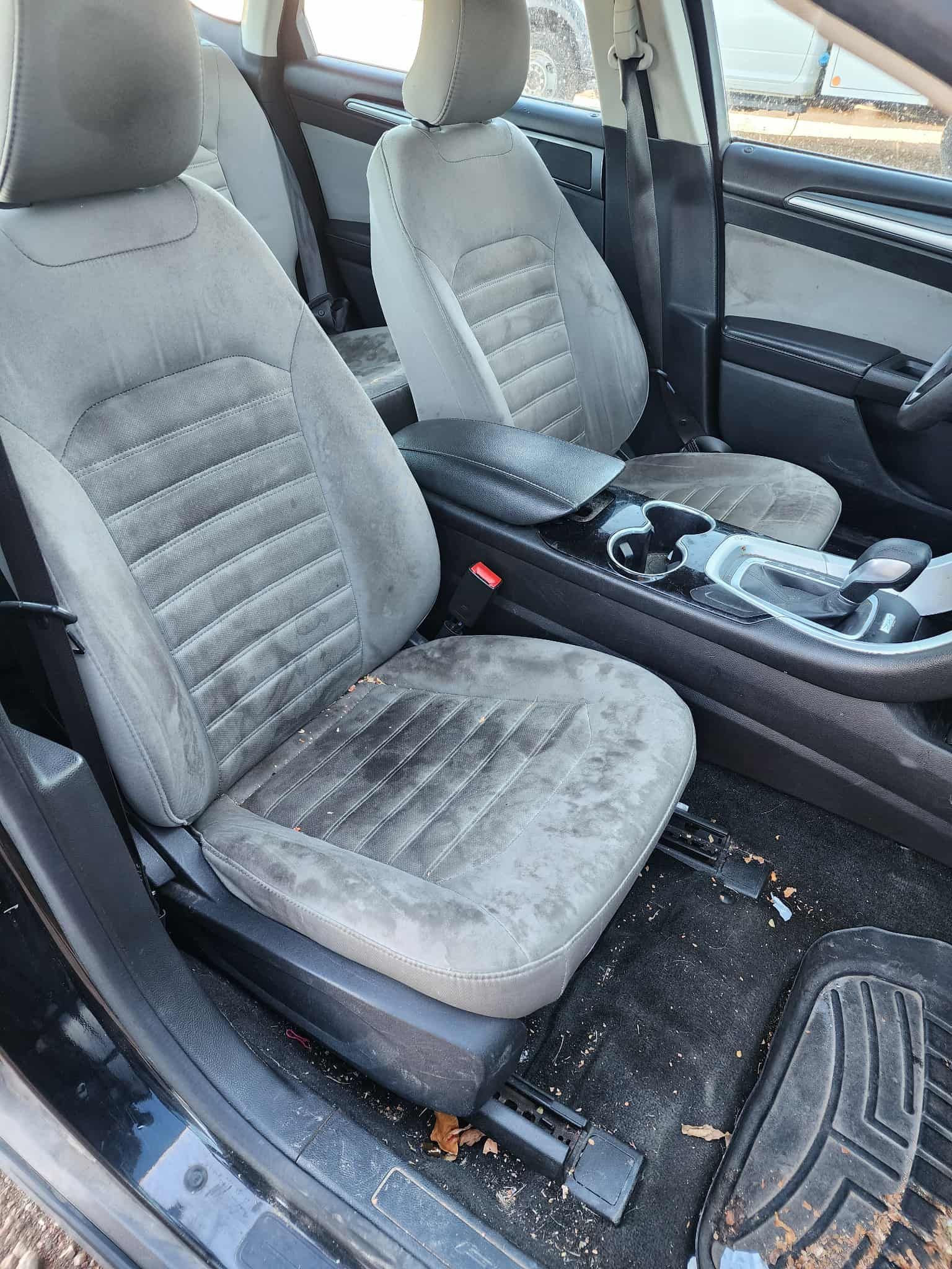 Dirty, stained gray car seats and interior in a vehicle.