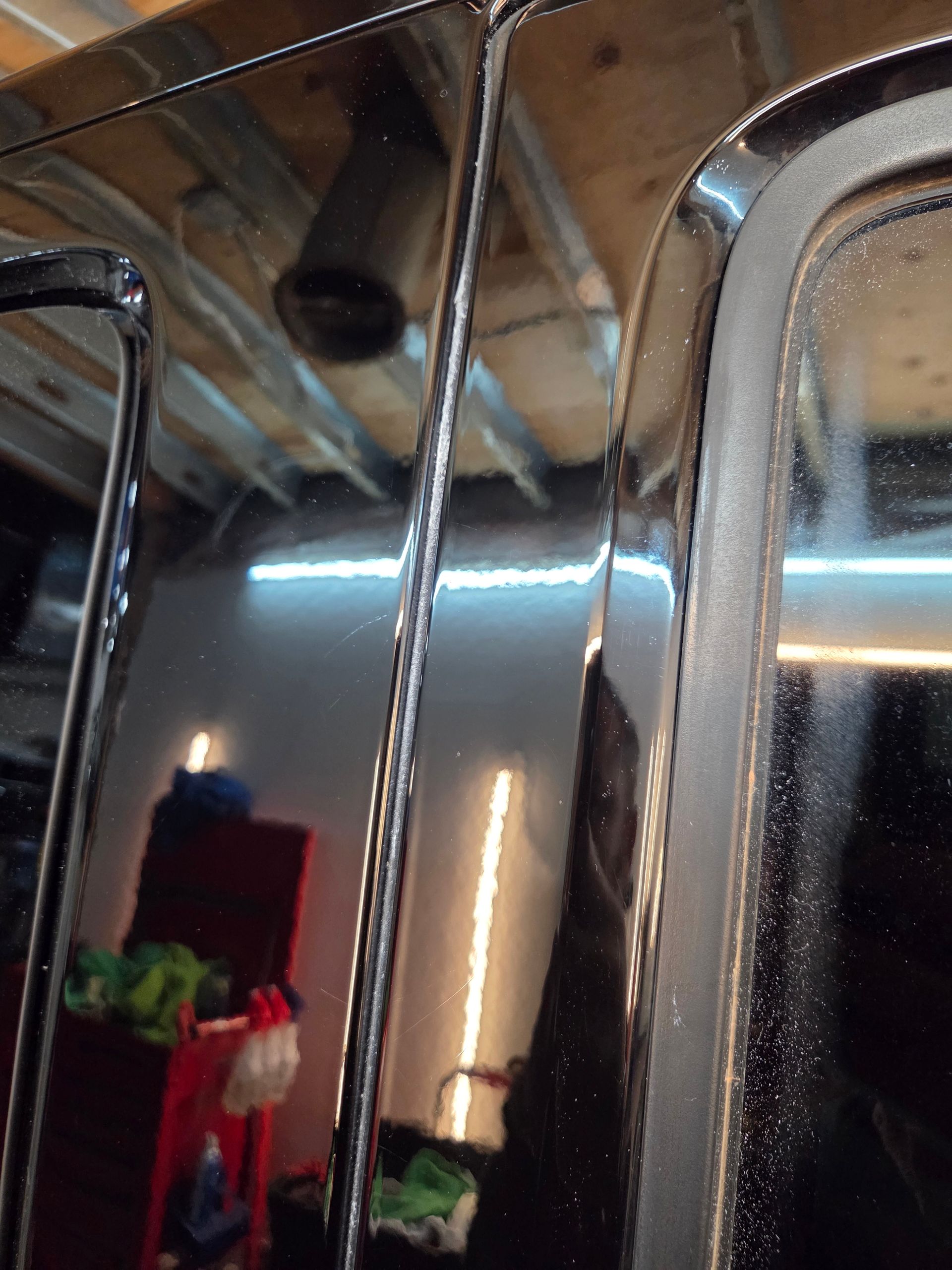 Black car door frame with antenna and window reflection.