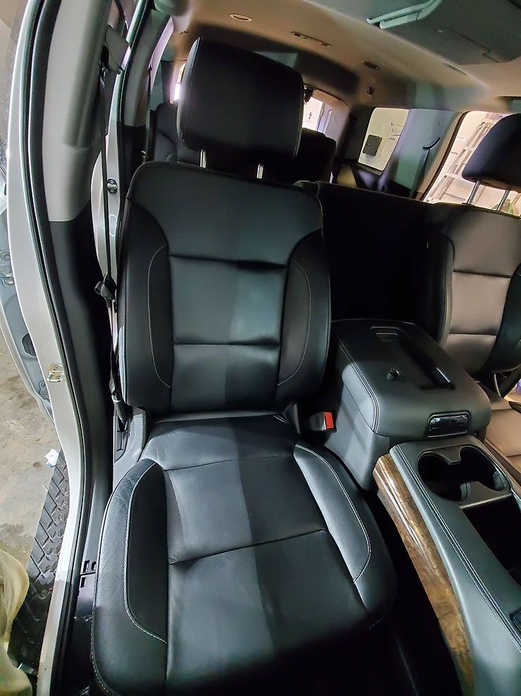 Black leather car seat with white stitching in a vehicle interior.