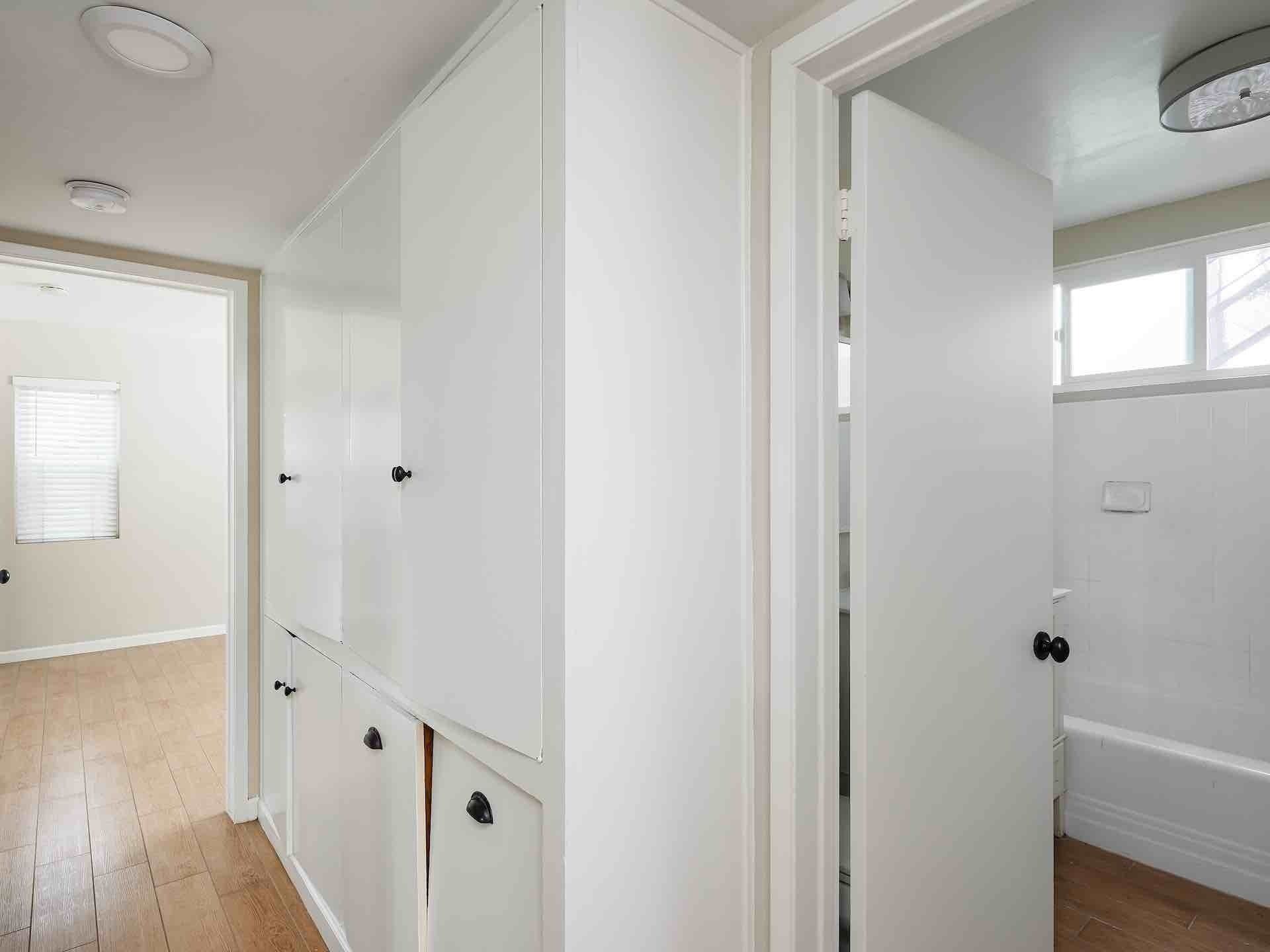 Hallway with built in cabinetry and doorway leading to bathroom