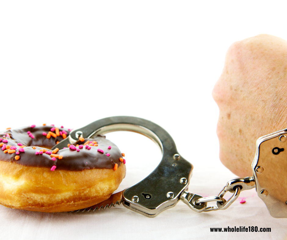 A hand with handcuffs and a donut with sprinkles on it